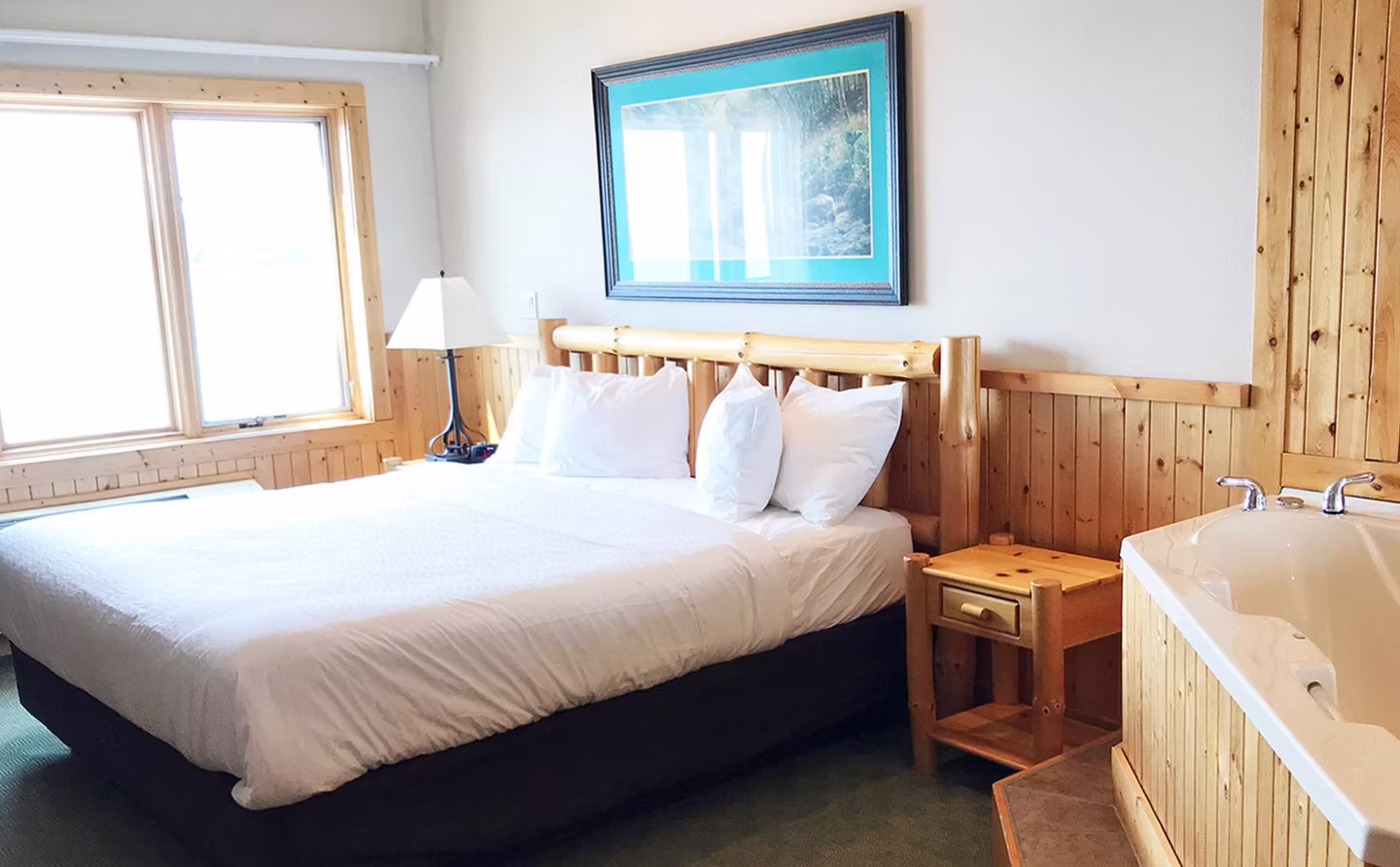 King bed beside a corner whirlpool tub with a Lake Superior view at Burlington Bay
