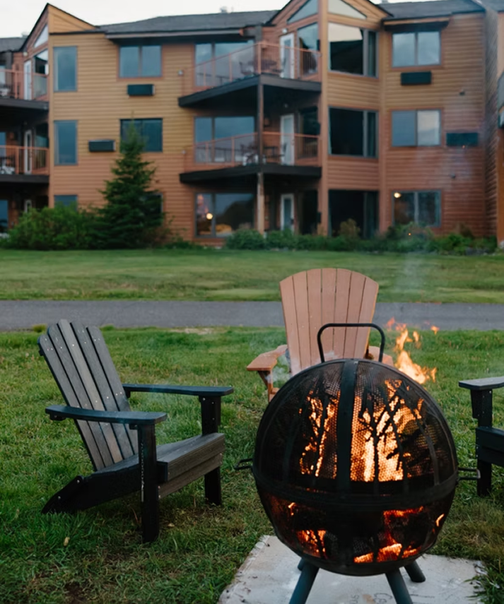 Adirondack chairs around a lit fire pit outside the lodging buildings at Superior Shores Resort