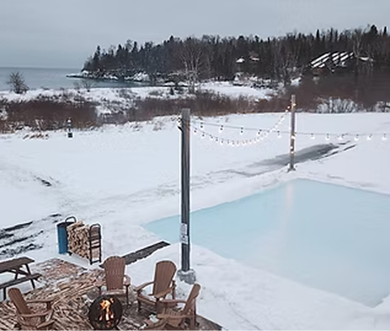 Outdoor pool and fire pit seating overlooking a snowy Lake Superior shoreline in winter