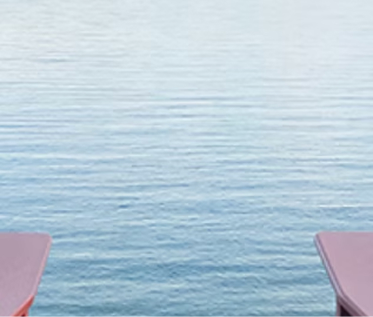Two lounge chairs facing the calm blue water of Lake Superior