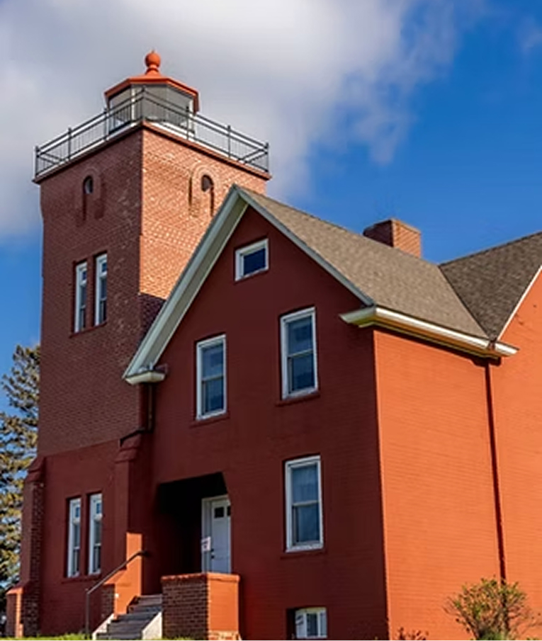 The red brick Two Harbors Lighthouse under a blue sky