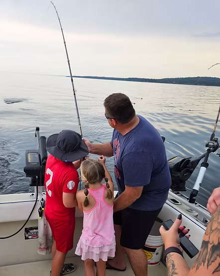 Family fishing from a charter boat on Lake Superior at sunset